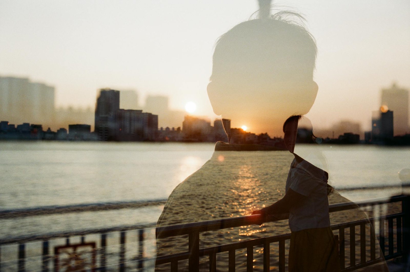silhouette of a man on a photo of a woman smiling on a bridge
